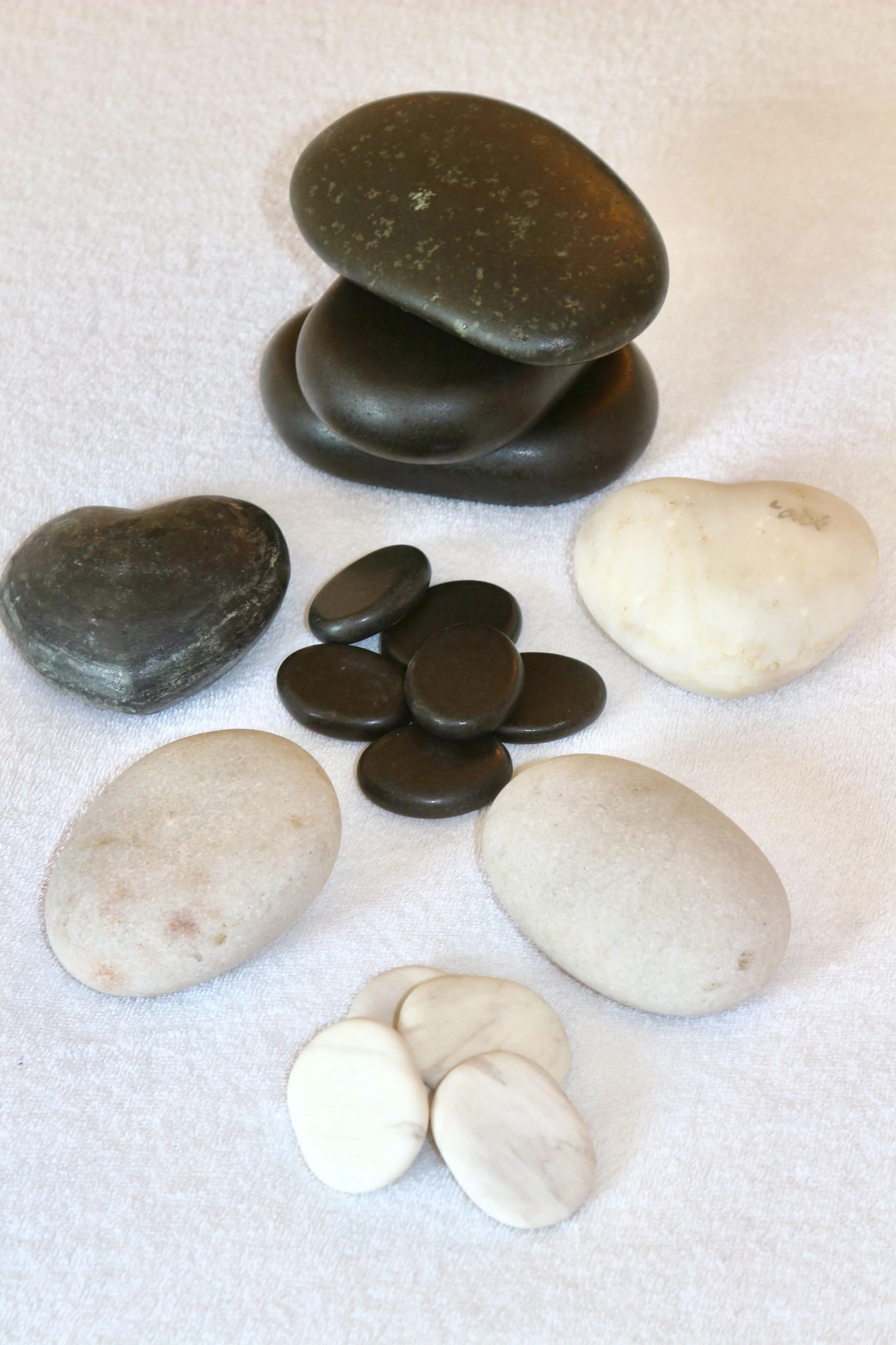 Hot and cold massage stones resting on cream linen